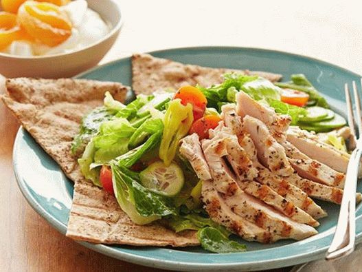 Fotosalat mit gegrilltem Hähnchen und getrockneten Aprikosen auf einem griechischen Kuchen